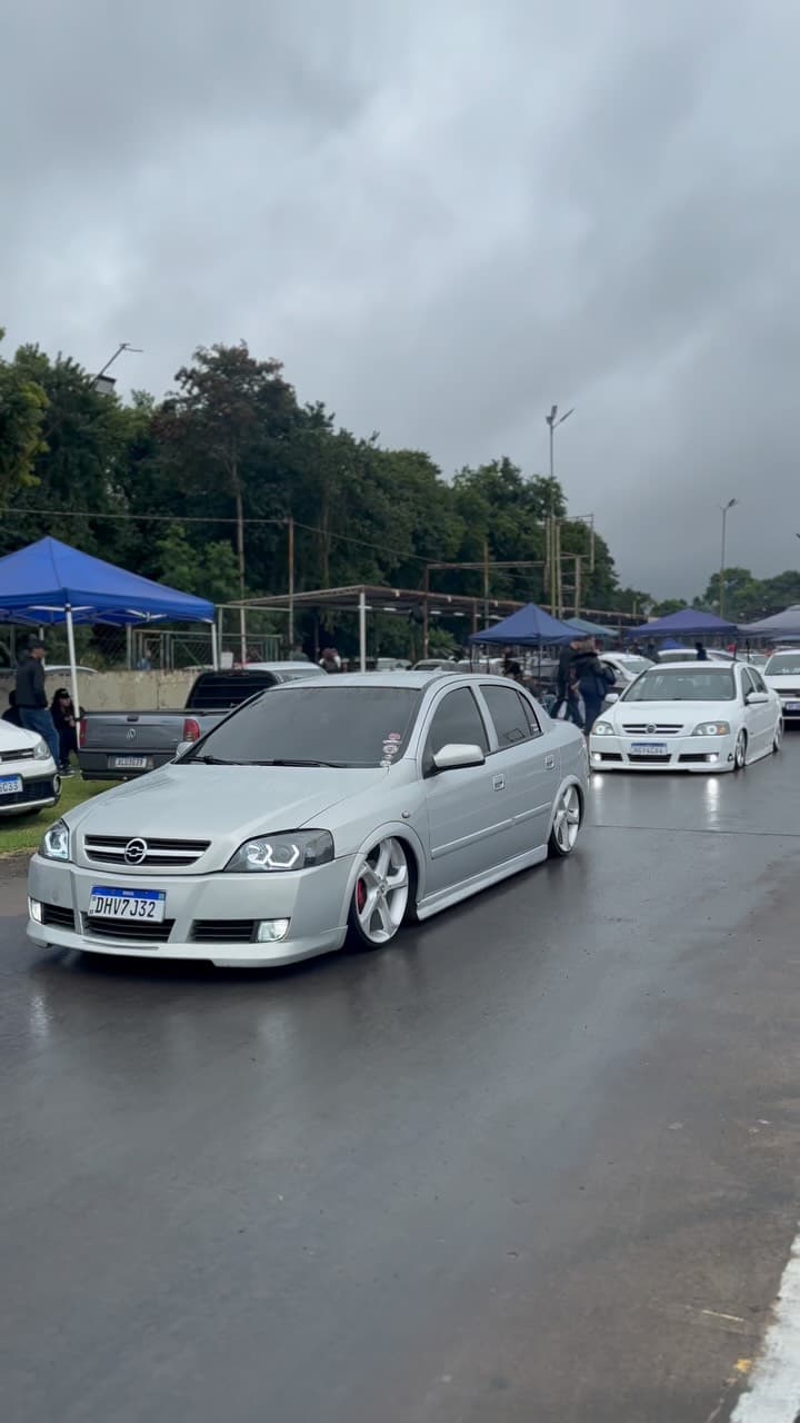 Comboio de carros rebaixados na avenida em dia de chuva